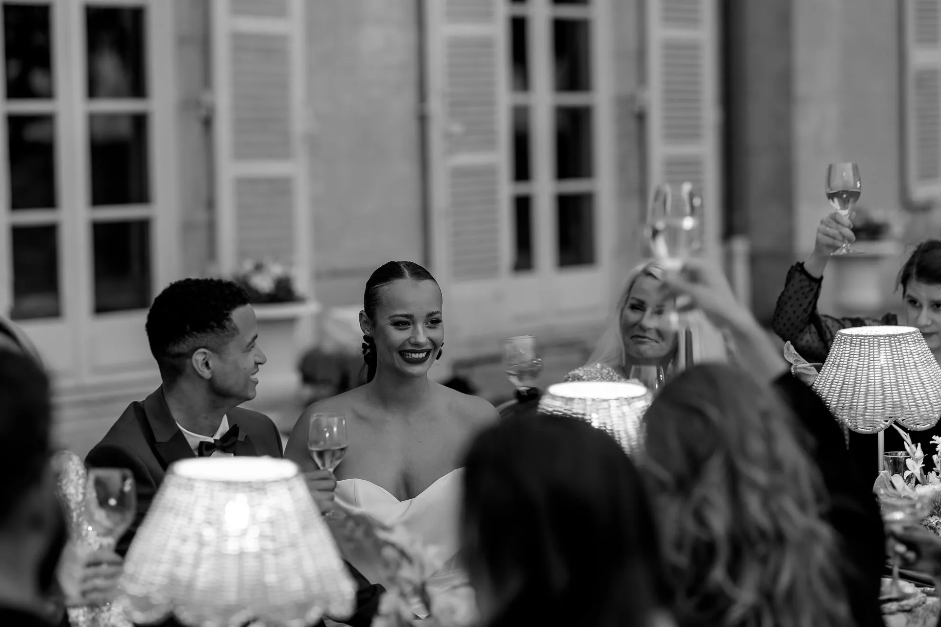 Schwarz-Weiß Brautpaar lacht mit Gästen bei Hochzeitsempfang am Chateau de Varennes in Frankreich